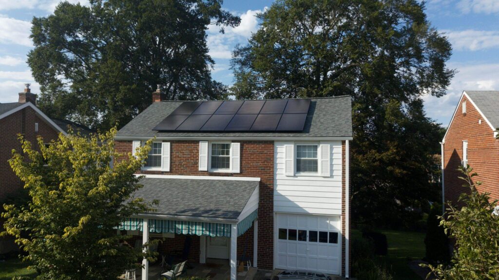 A house with a solar panel on the roof, demonstrating sustainable energy projects.