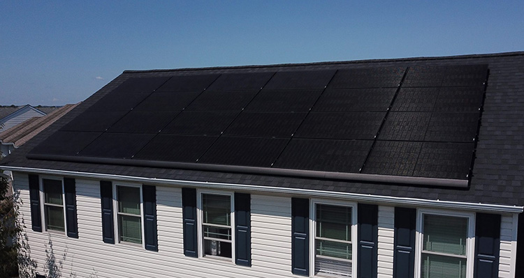 A black solar panel on the roof of a home.